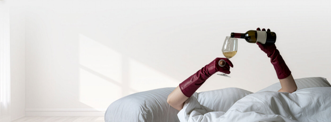 A woman reclining, pouring wine into a glass held by burgundy-gloved hands
